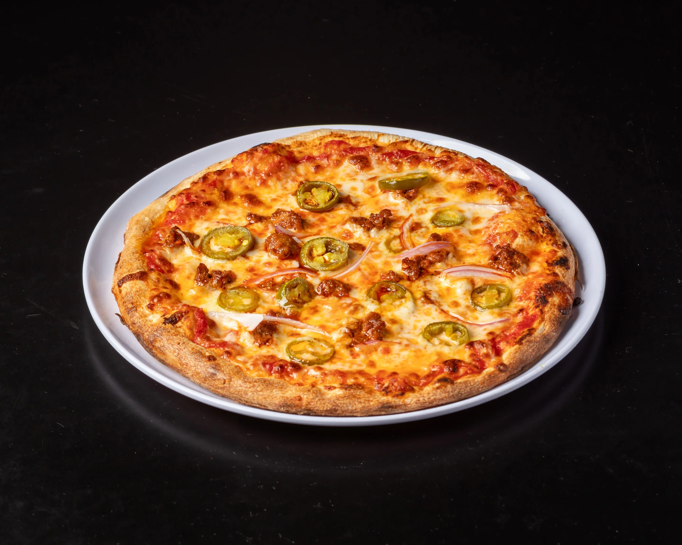 A round pizza topped with ham and pineapple chunks on a cheesy tomato base.
