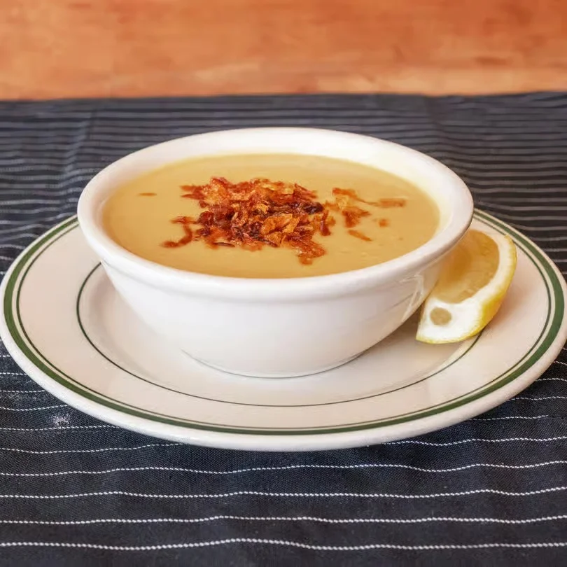 Creamy soup topped with crispy onions and a lemon wedge.