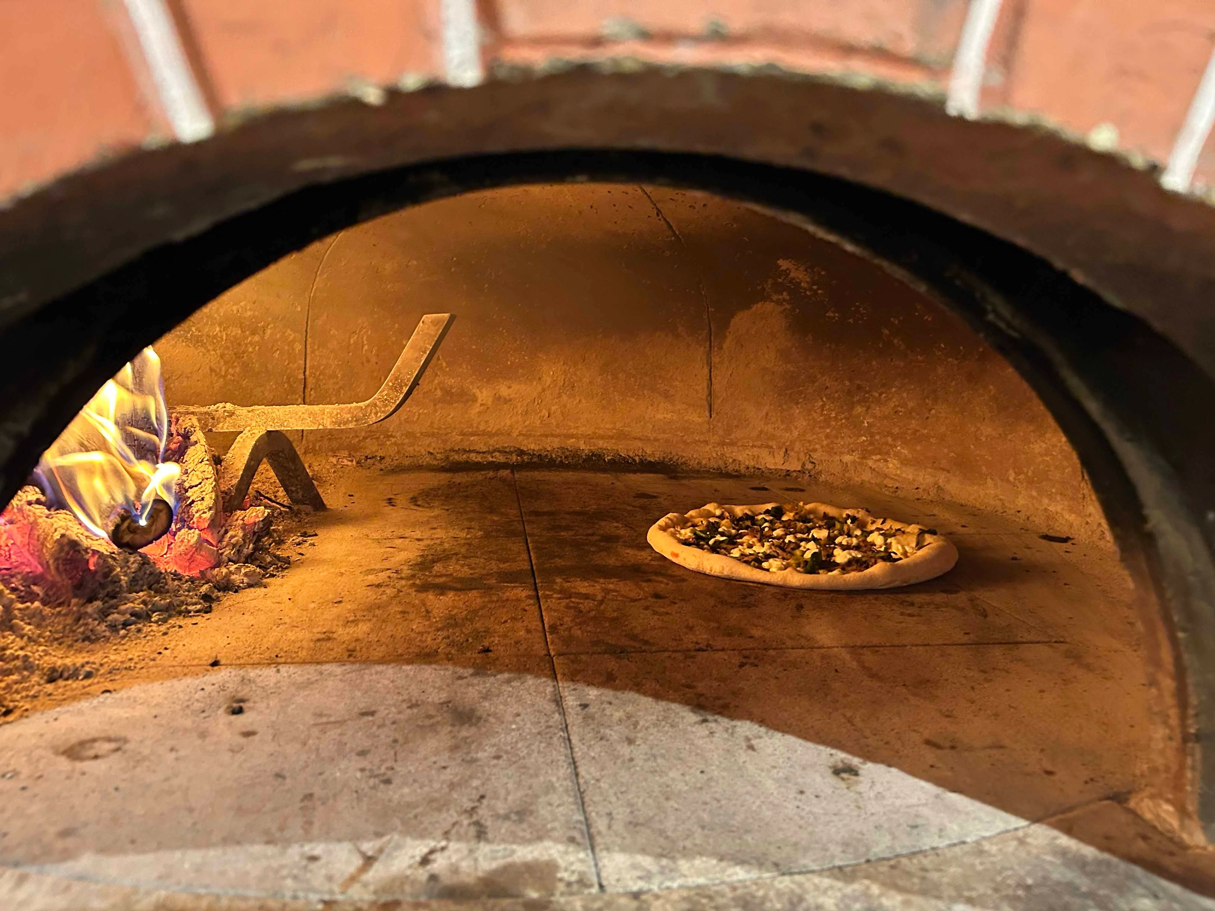 Wood-fired pizza baking in a traditional oven