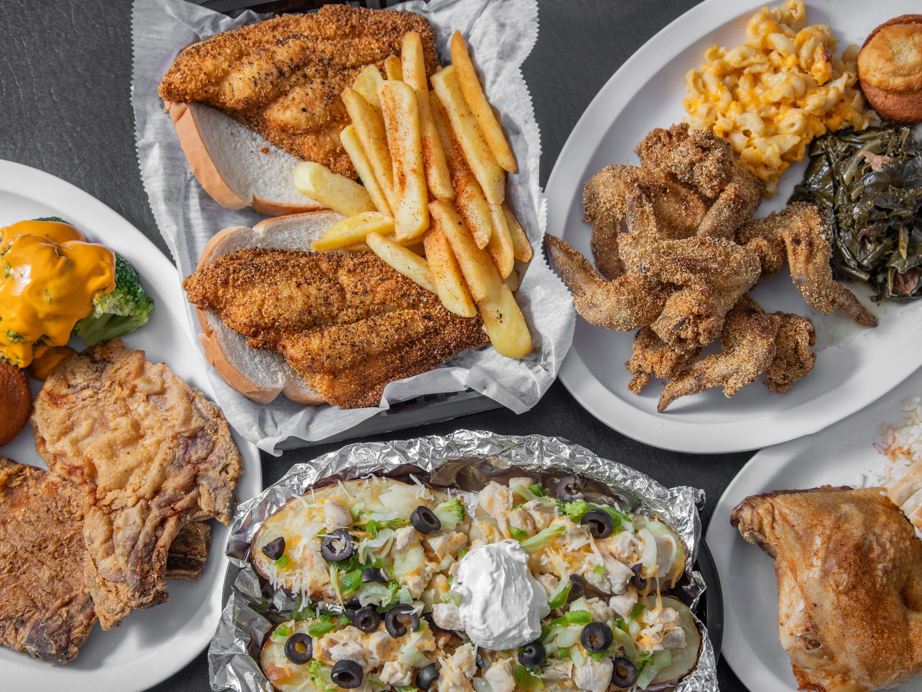 Southern comfort food spread with fried fish, chicken, fries, and loaded baked potato