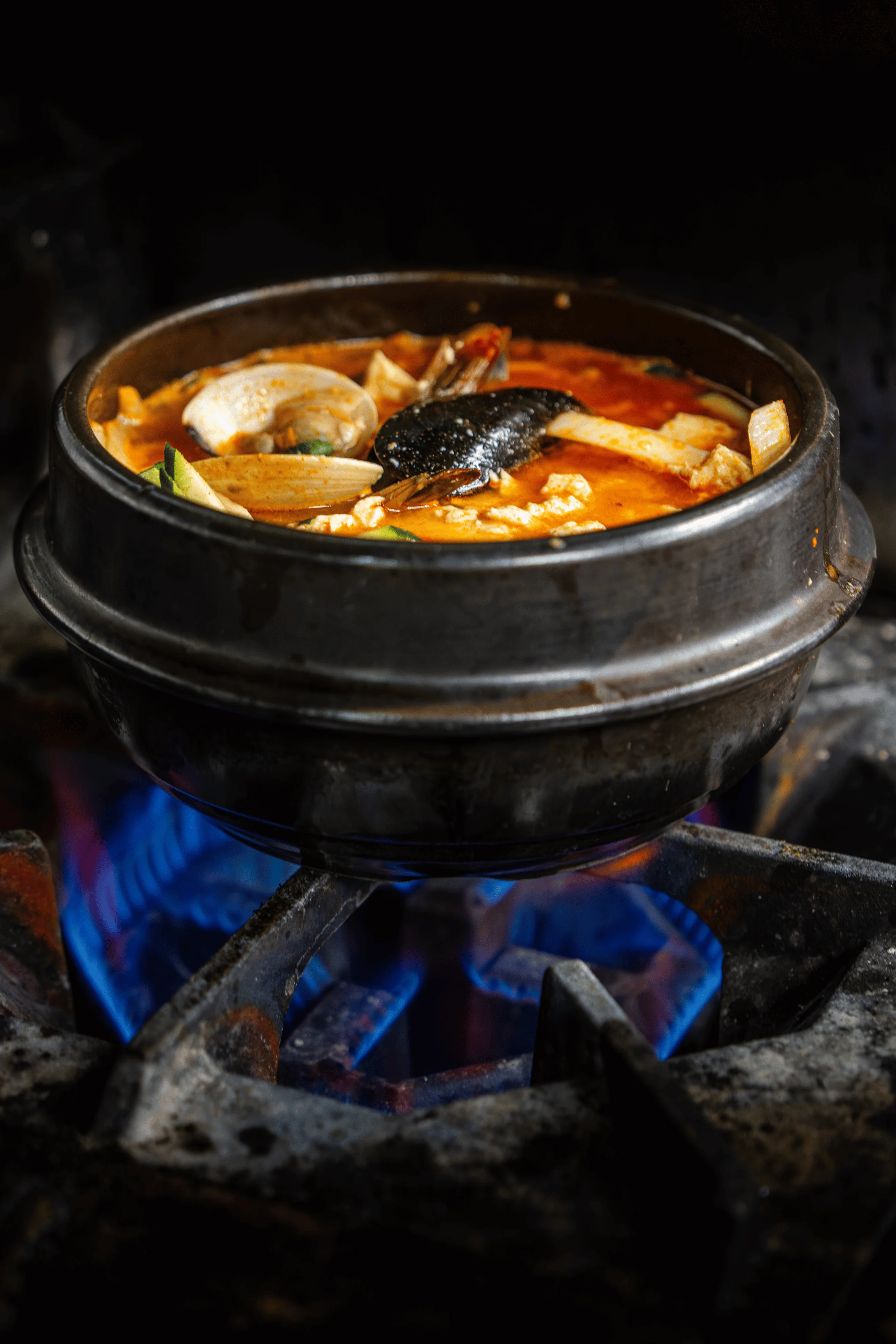 Korean seafood jjigae in a stone pot on a gas stove