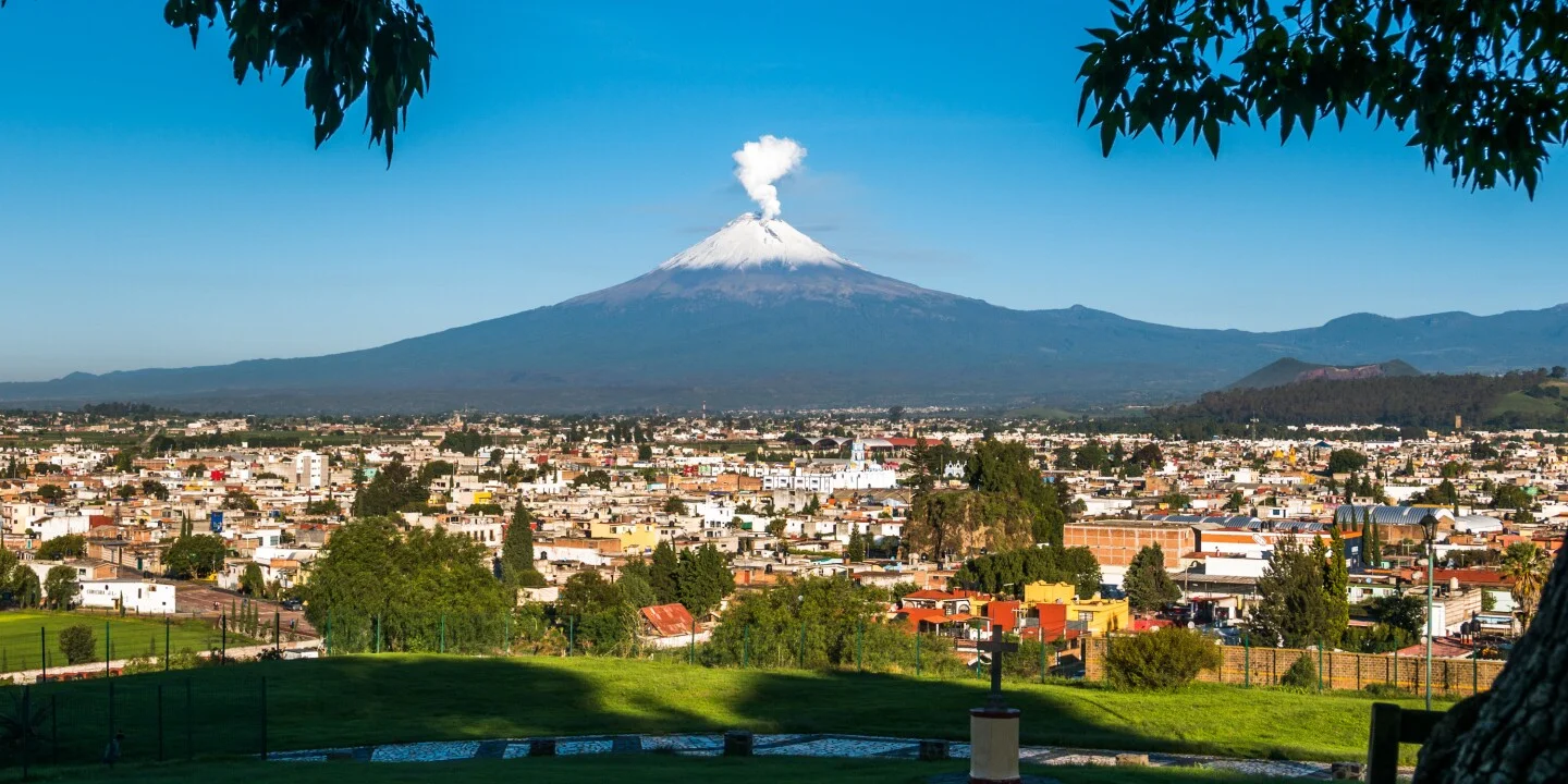 View of a city with a volcano in the background under a clear blue sky