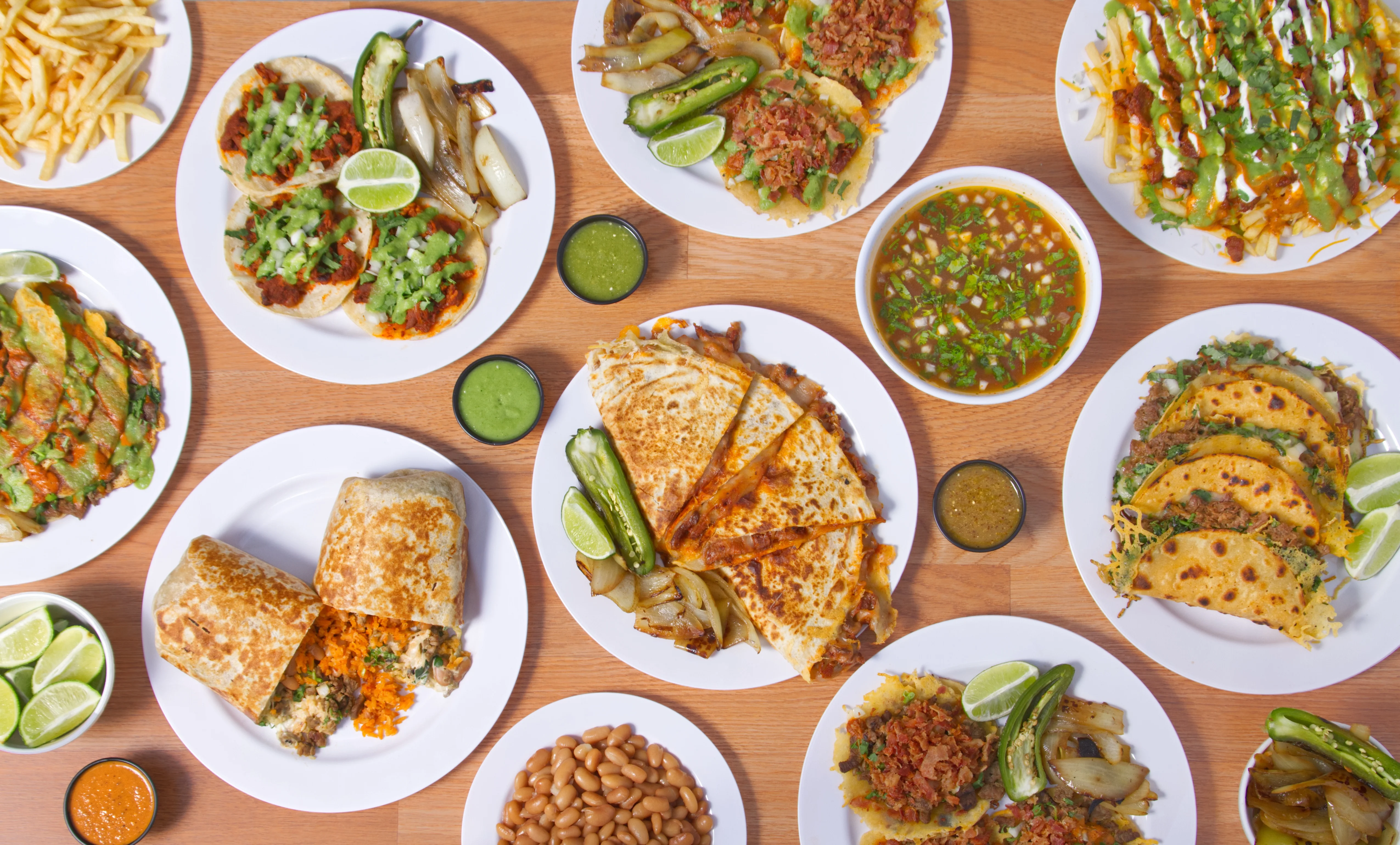 Assorted Mexican dishes including tacos and quesadillas on a wooden table