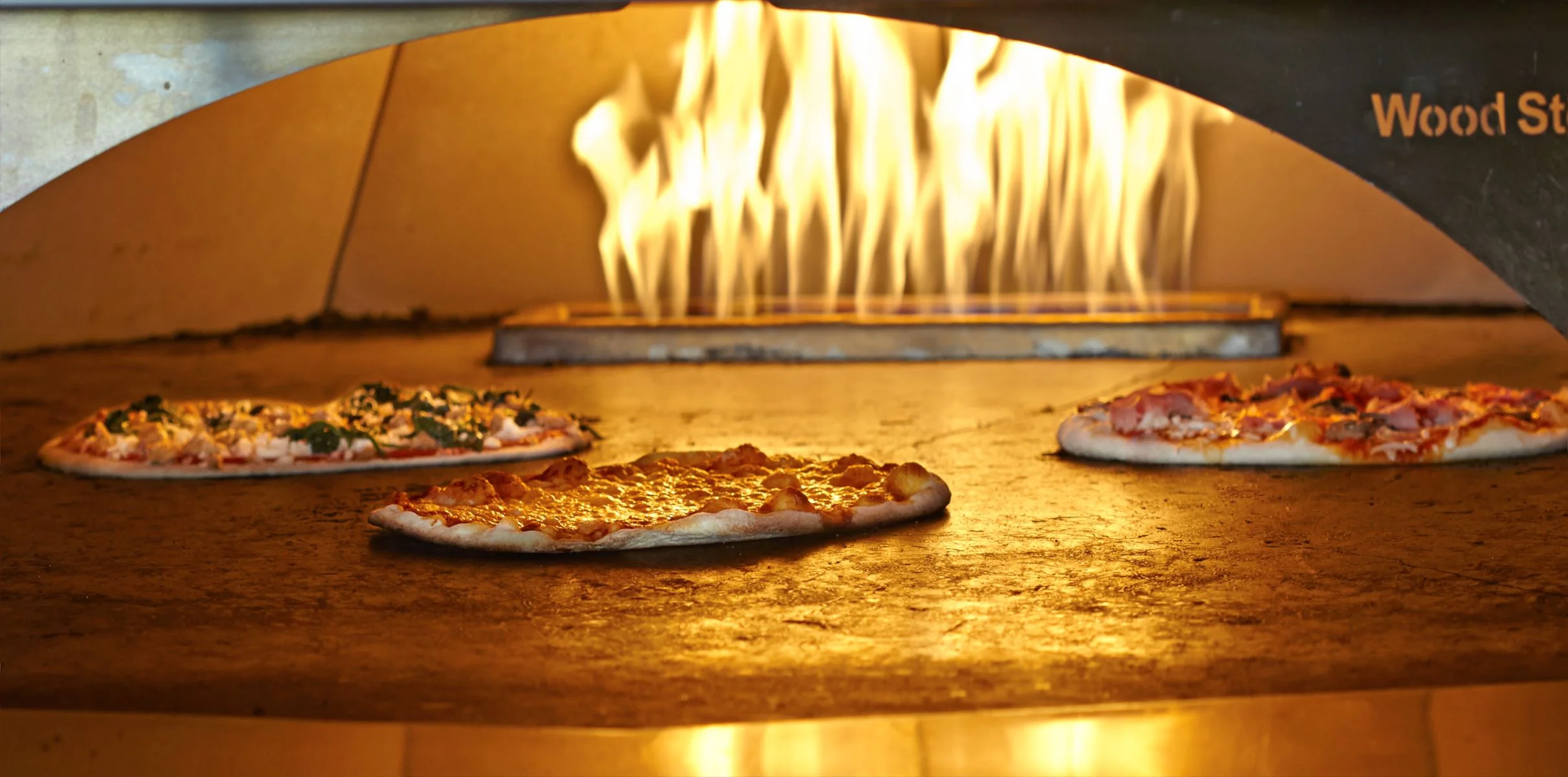 A pizza oven baking 3 pizzas, Cheese pizza, Garden Pizza, Carne Combo Pizza