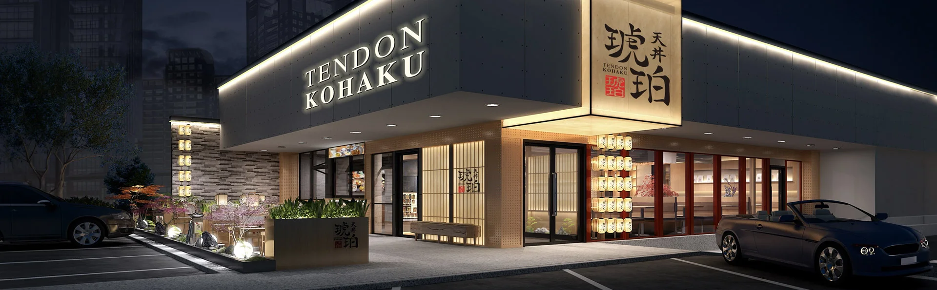 The storefront of Tendon Kohaku at night, featuring a contemporary dark facade with illuminated white signage. 