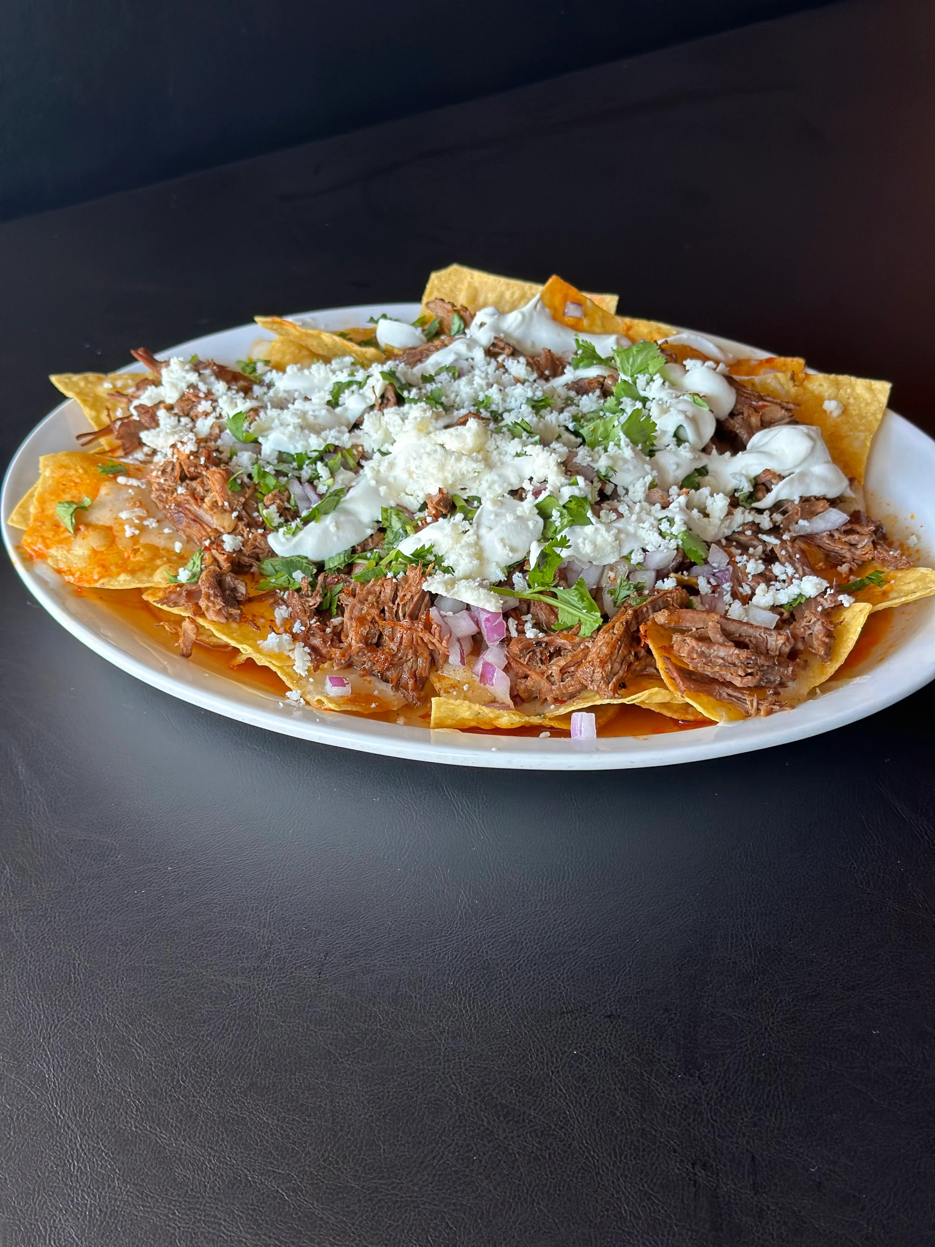 Plate of Mexican nachos topped with shredded beef and cheese