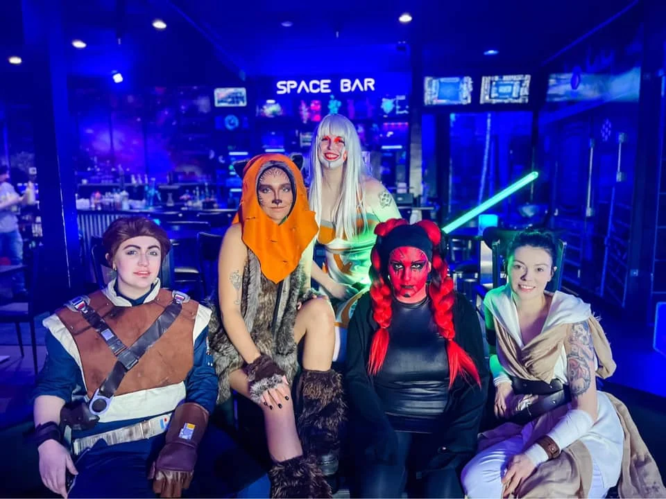 Group of cosplayers in a vibrant space-themed bar setting