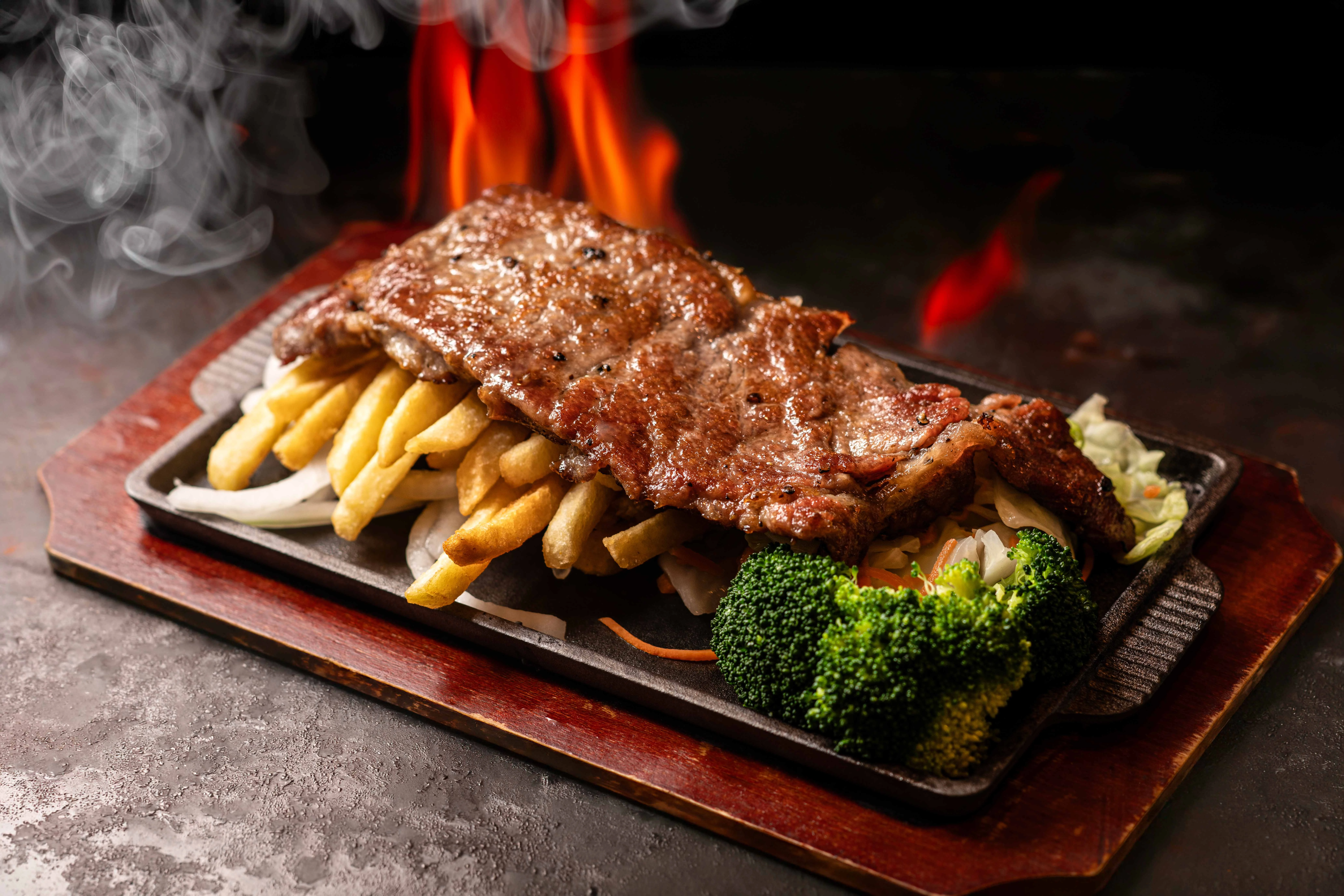 Sizzling steak fajitas with fries and vegetables on a hot plate