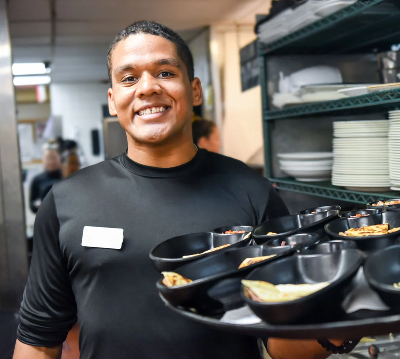 Restaurant staff serving dishes in black bowls