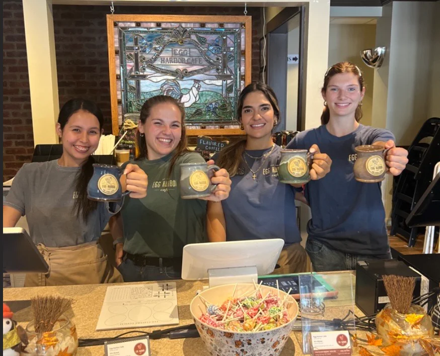Friendly staff at Egg Harbor Cafe holding coffee mugs