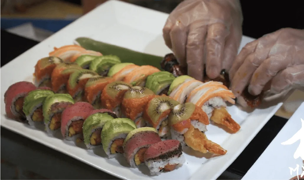 Chef's hands finishing a rainbow roll with tuna, salmon and avocado at Mahzu East Windsor
