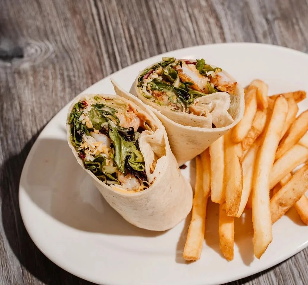 Grilled chicken wrap with fries on a white plate