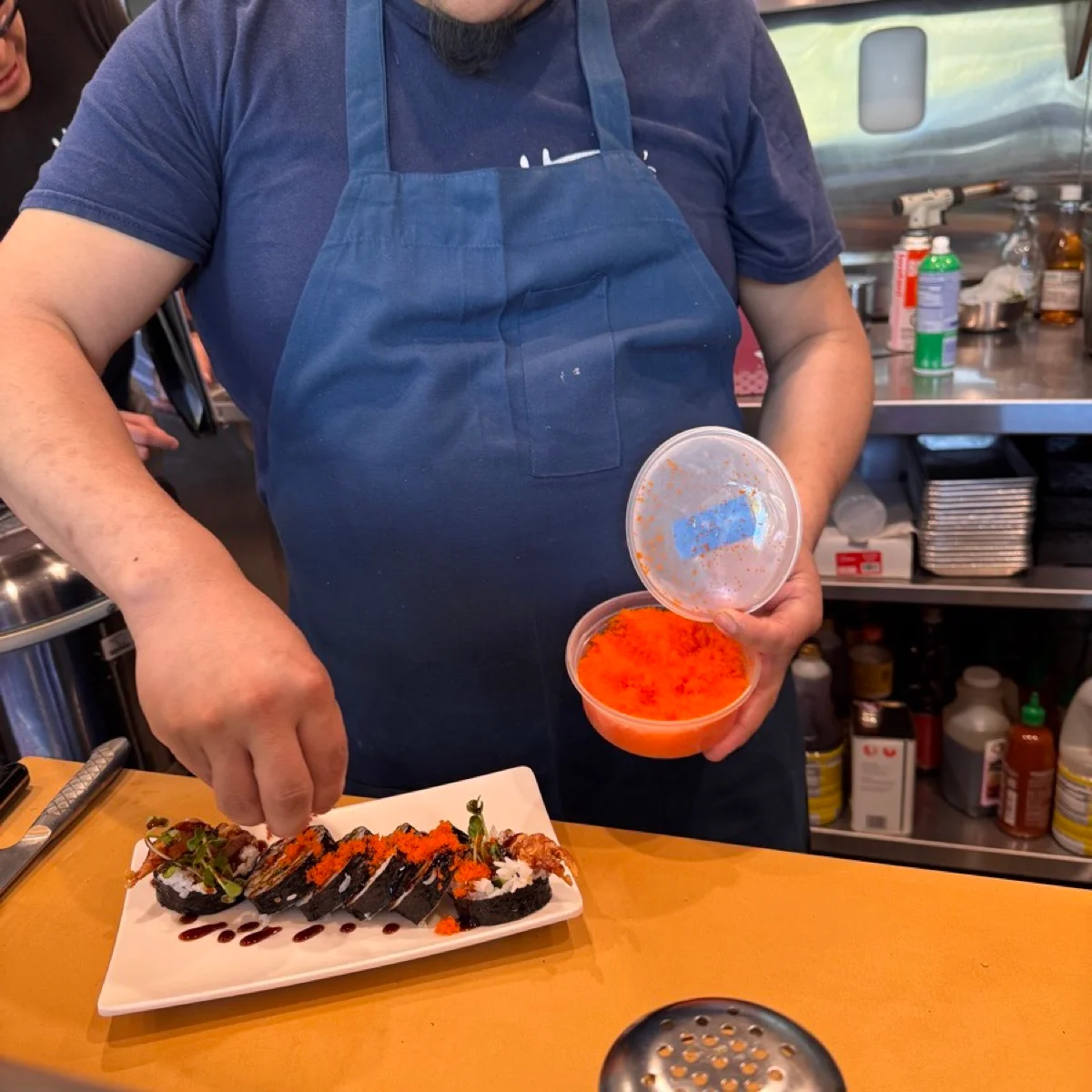 A grin, a fresh roll, and a scoop of bright tobiko at the Malibu Sushi bar