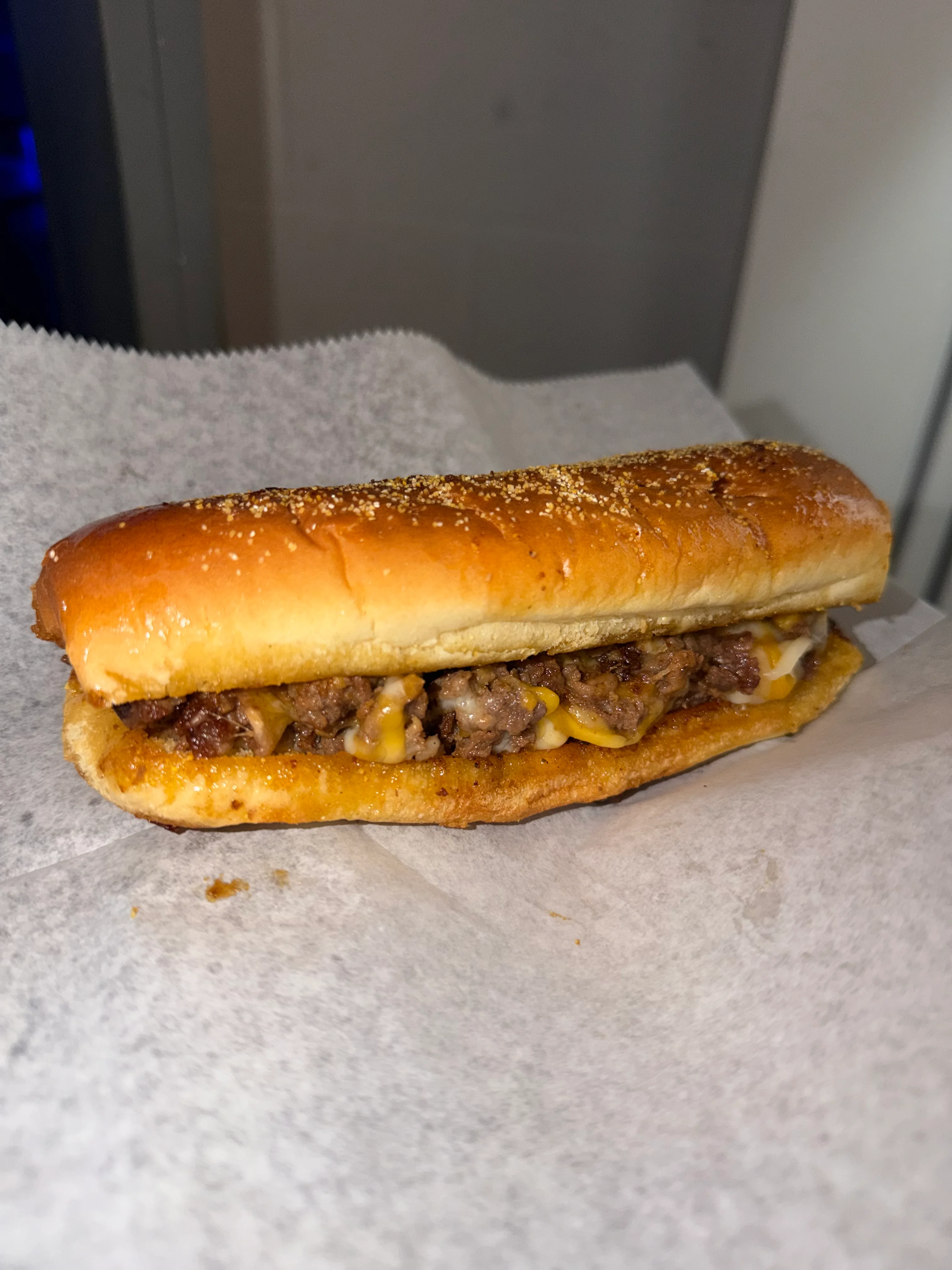 A delicious hot dog filled with seasoned meat and melted cheese in a toasted bun.