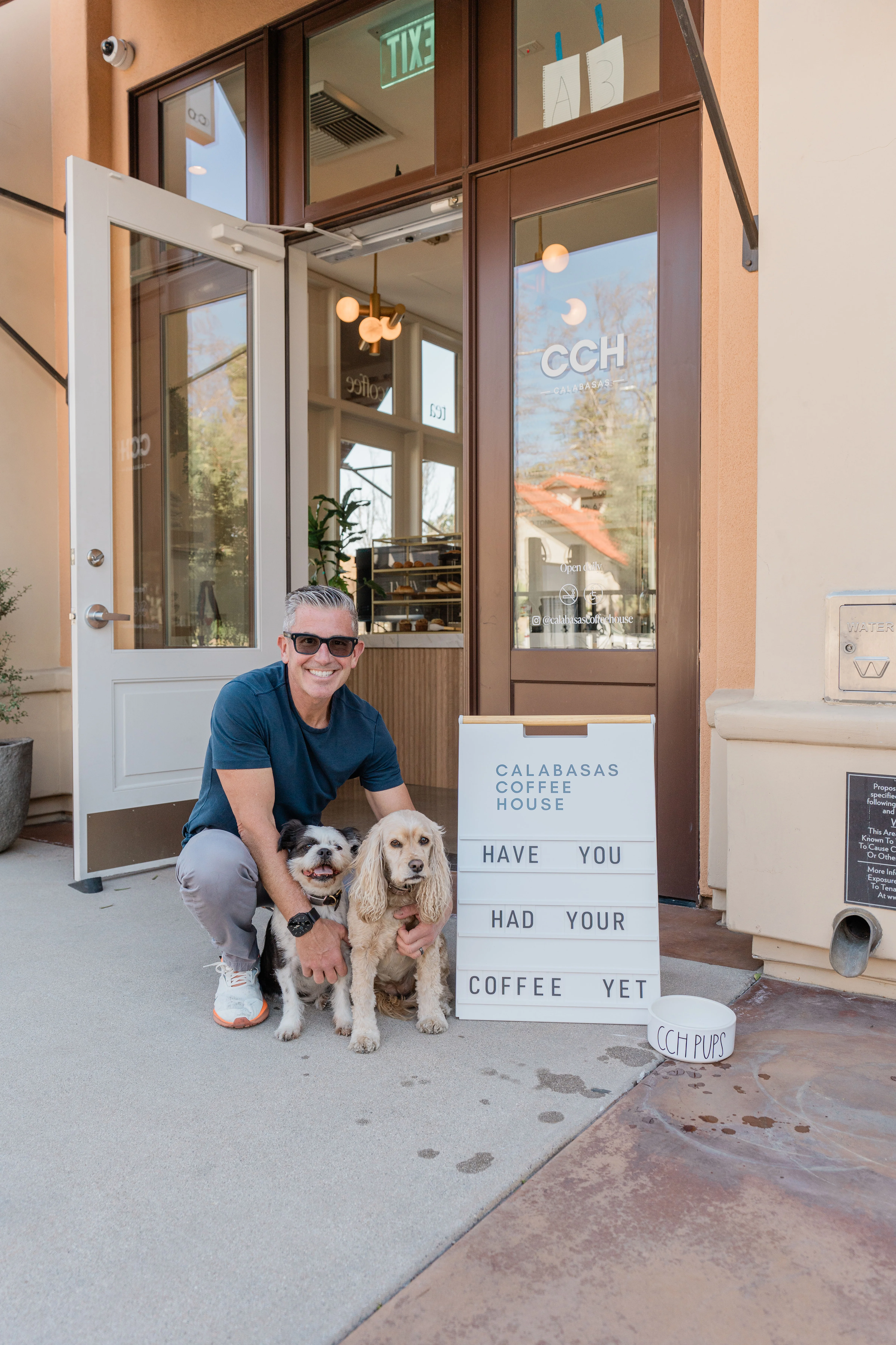 Person with two dogs outside Calabasas Coffee House