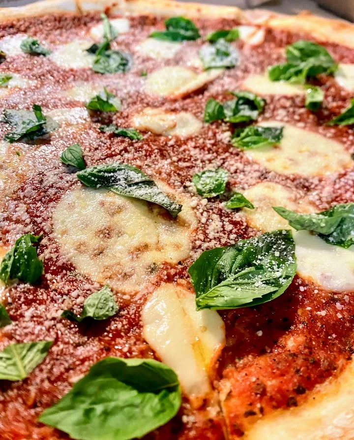 Margherita pizza topped with fresh basil and mozzarella