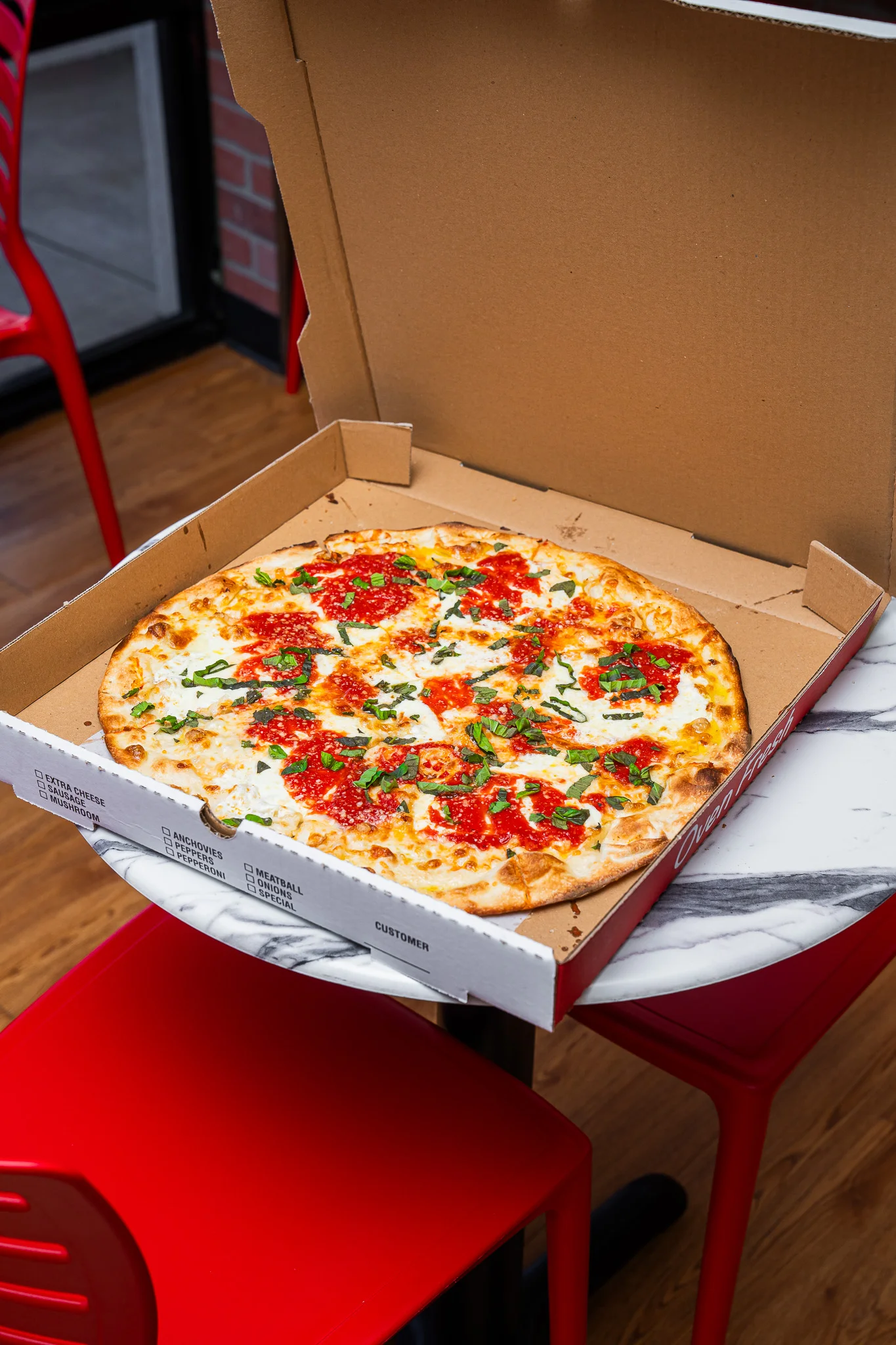 Fresh Margherita pizza in a takeout box