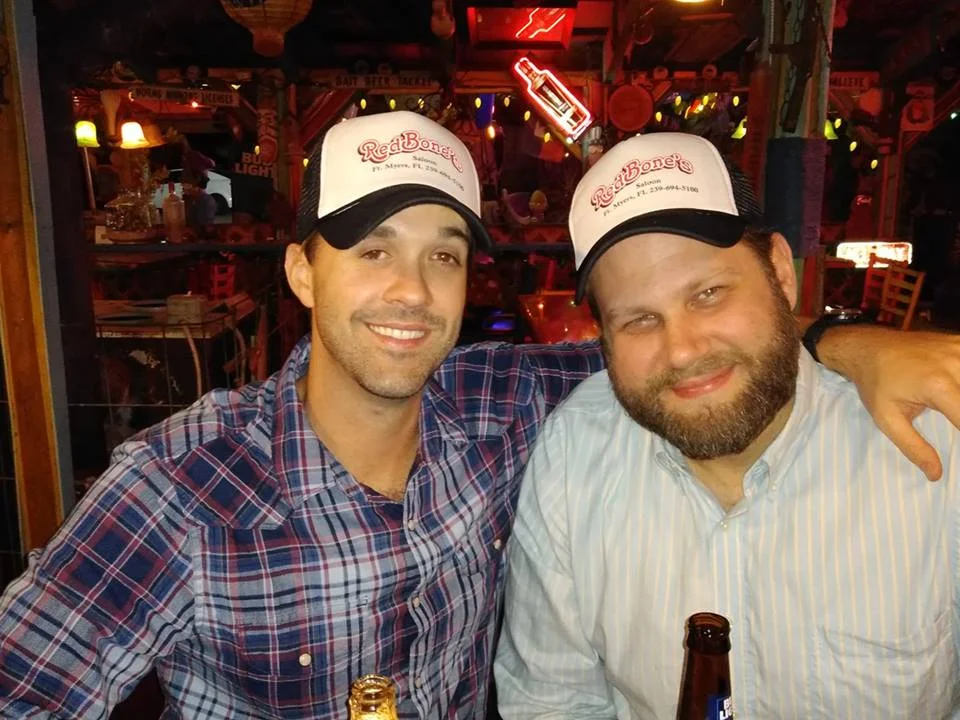 Two friends enjoying drinks in a lively bar atmosphere