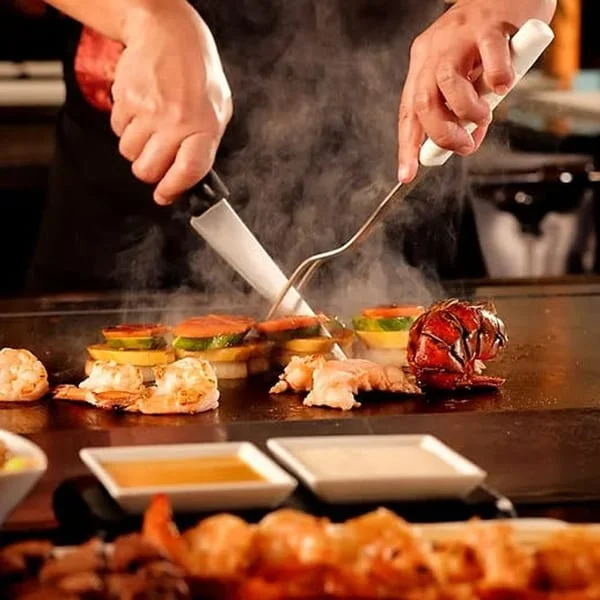 Teppanyaki chef grilling seafood and vegetables at a Japanese restaurant
