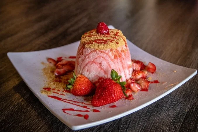 Strawberry Cheesecake snow topped with graham cracker crumbs, strawberry sauce, white chocolate sauce, condensed milk and whipped cream with strawberry pieces and strawberry cheesecake bites