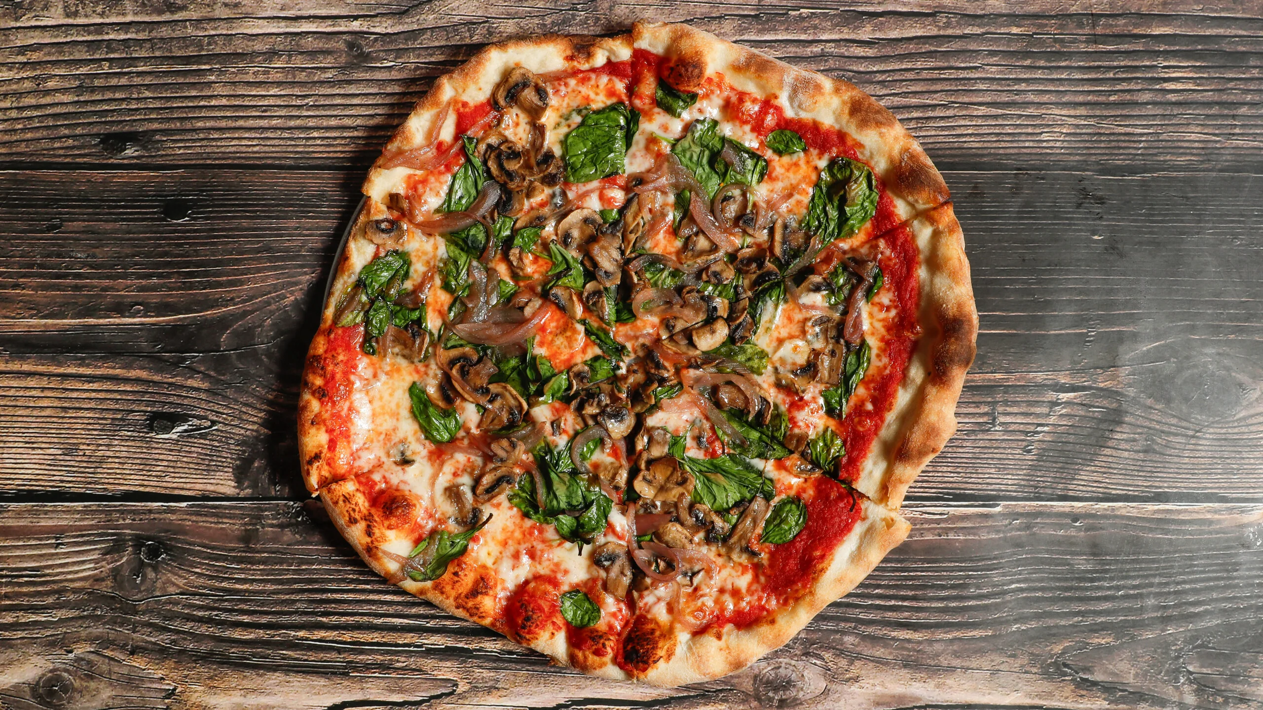 Freshly baked pizza topped with spinach and dollops of creamy cheese