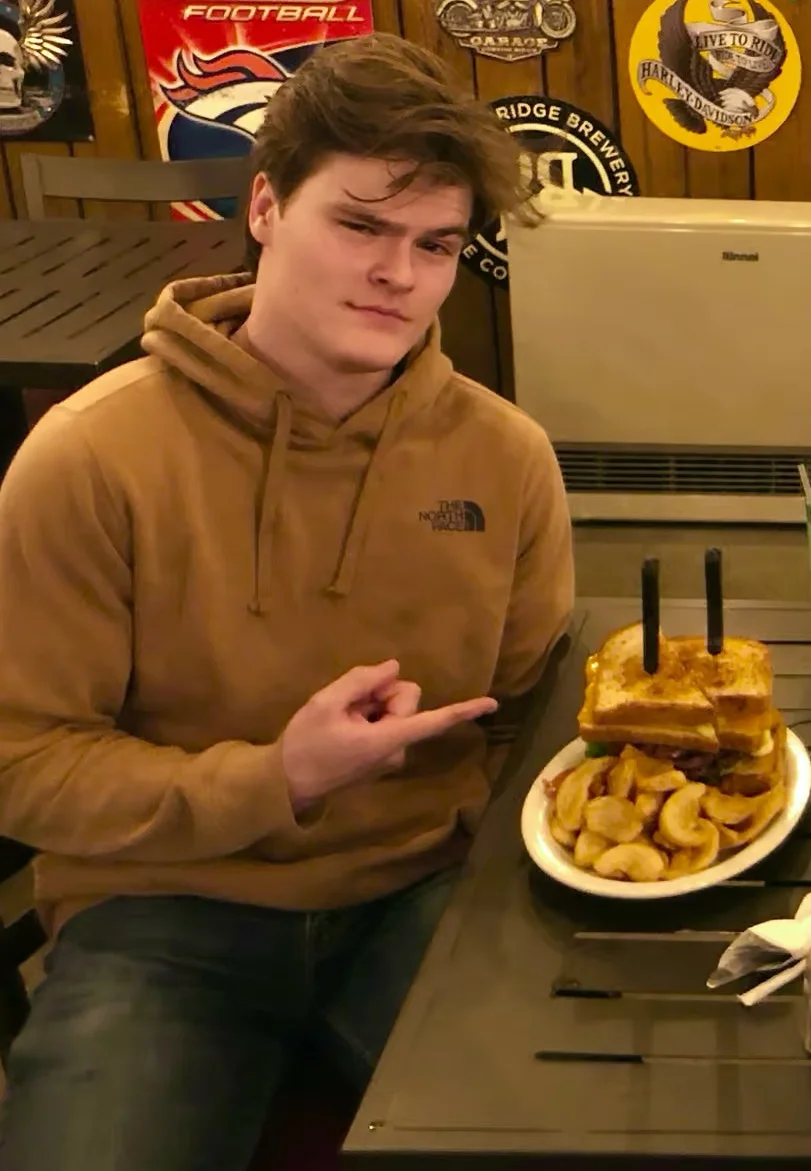 Giant stacked burger with fries in a casual restaurant setting