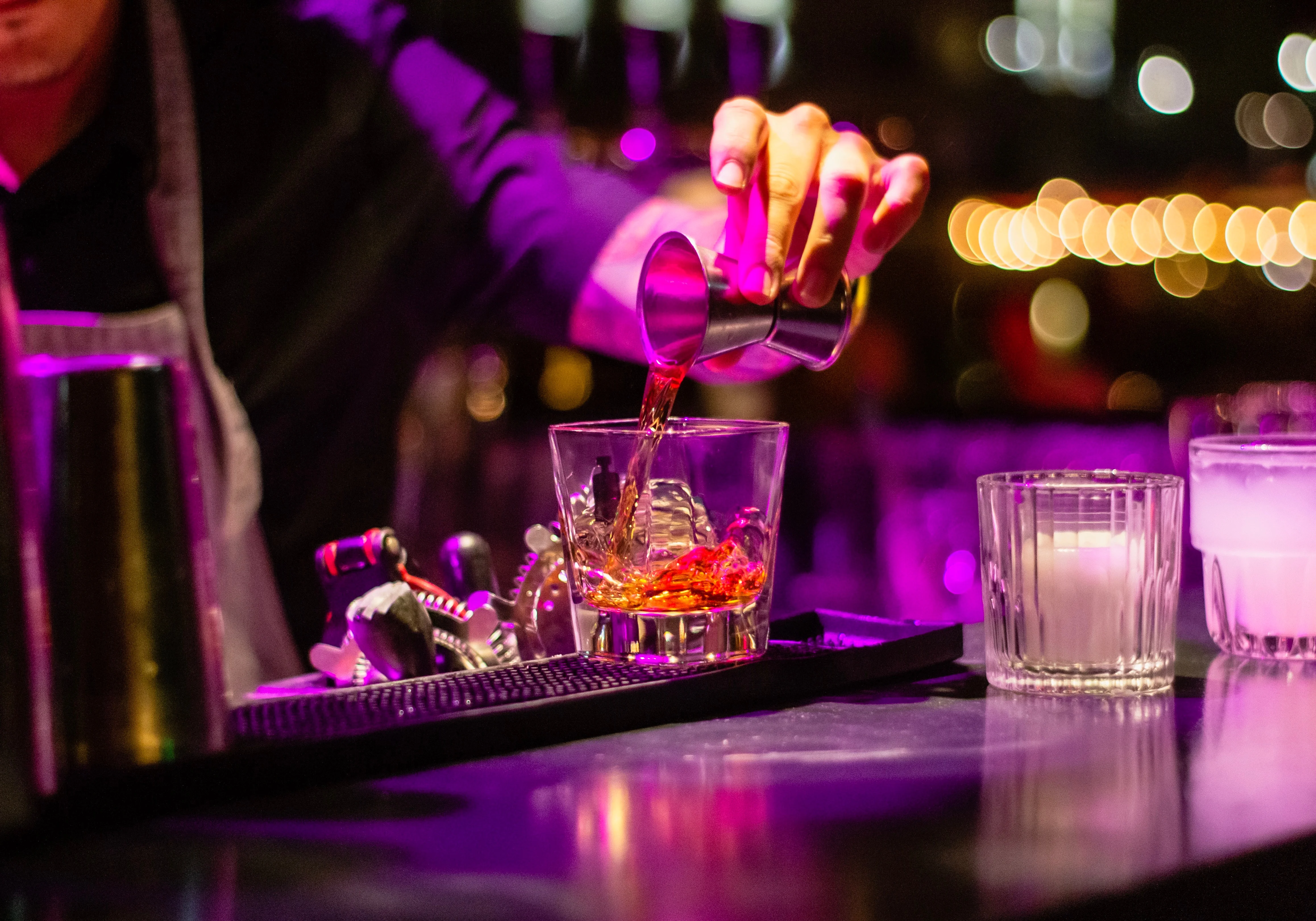 Bartender pouring a cocktail at a vibrant bar