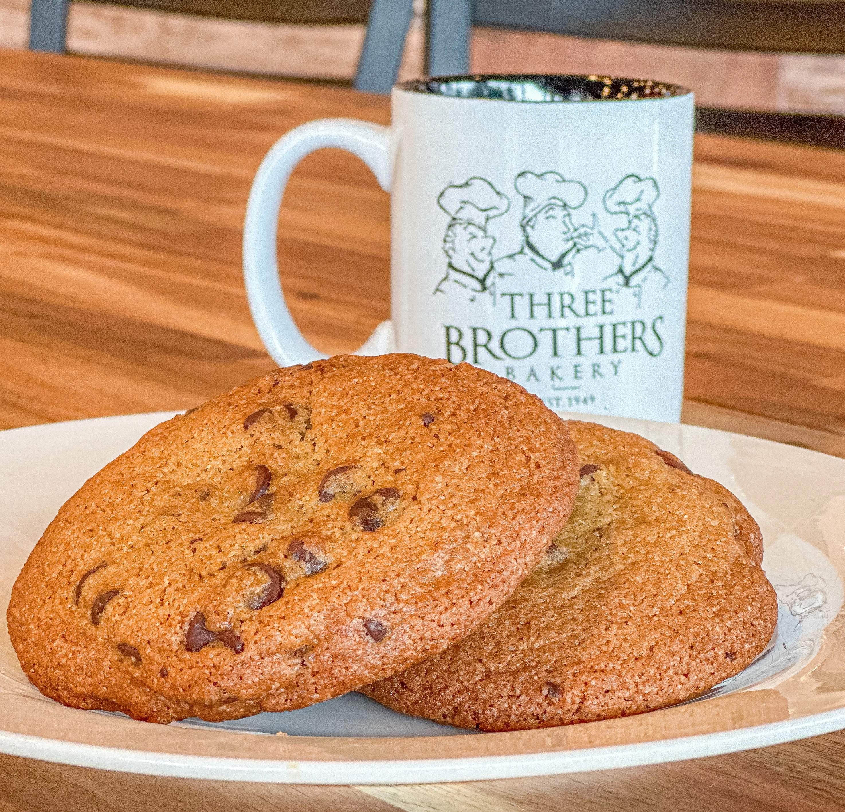 Freshly baked chocolate chip cookies on a plate with a coffee mug