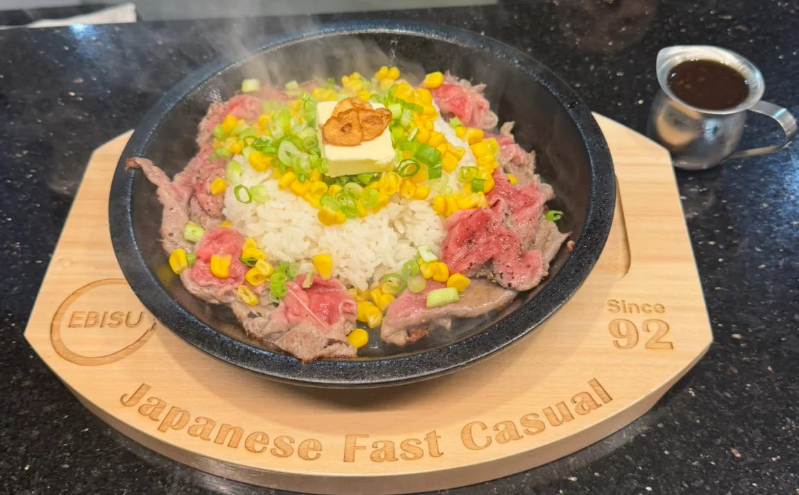 Japanese gyudon with rice and vegetables in a sizzling stone bowl