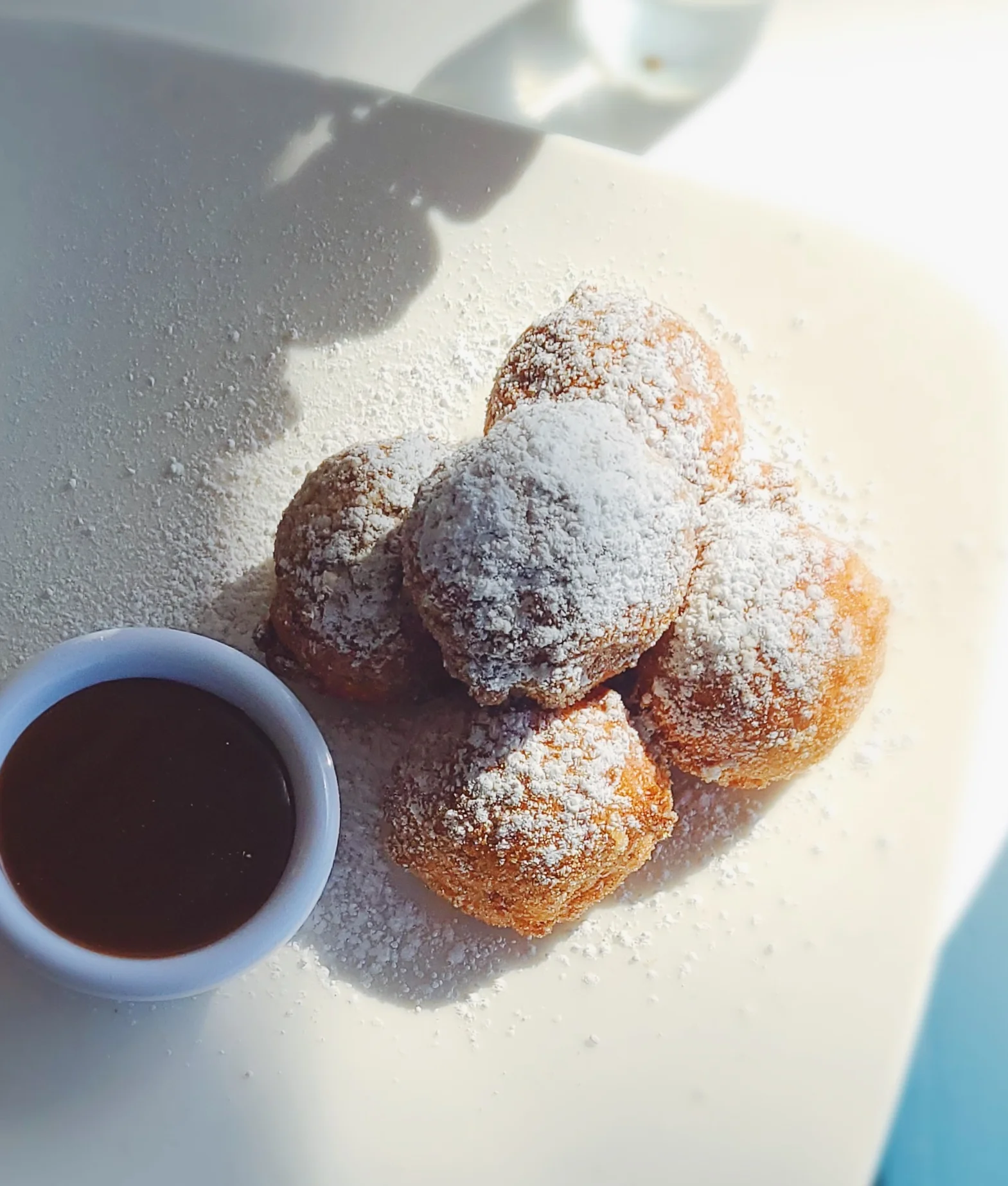 Delicious beignets dusted with powdered sugar and served with chocolate sauce