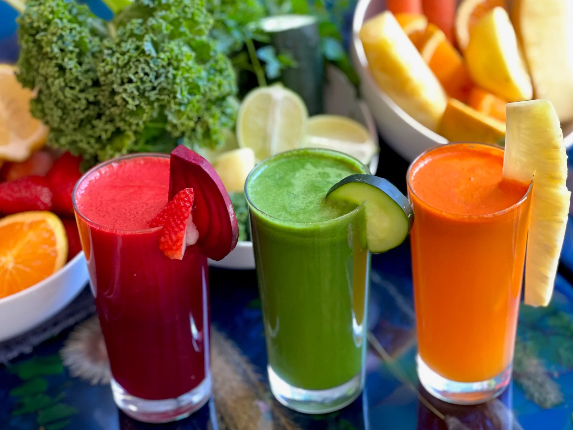 Colorful fresh juice trio in glasses with fruits and greens