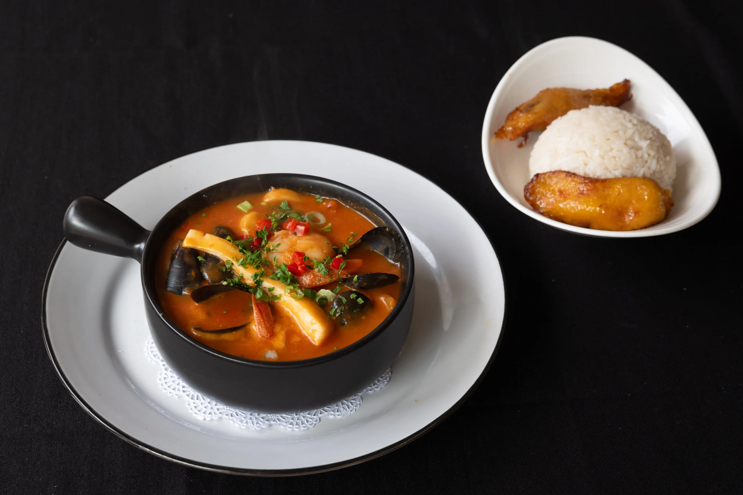 Spicy Caribbean seafood soup with rice and fried plantains