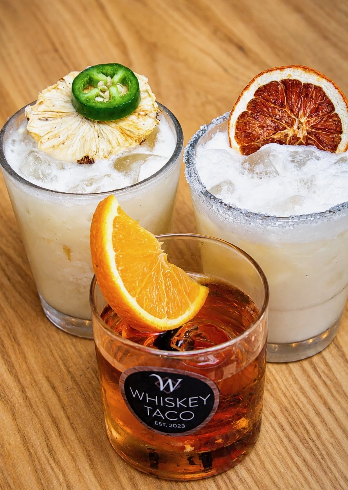 Colorful cocktails at a bar with garnishes and ice