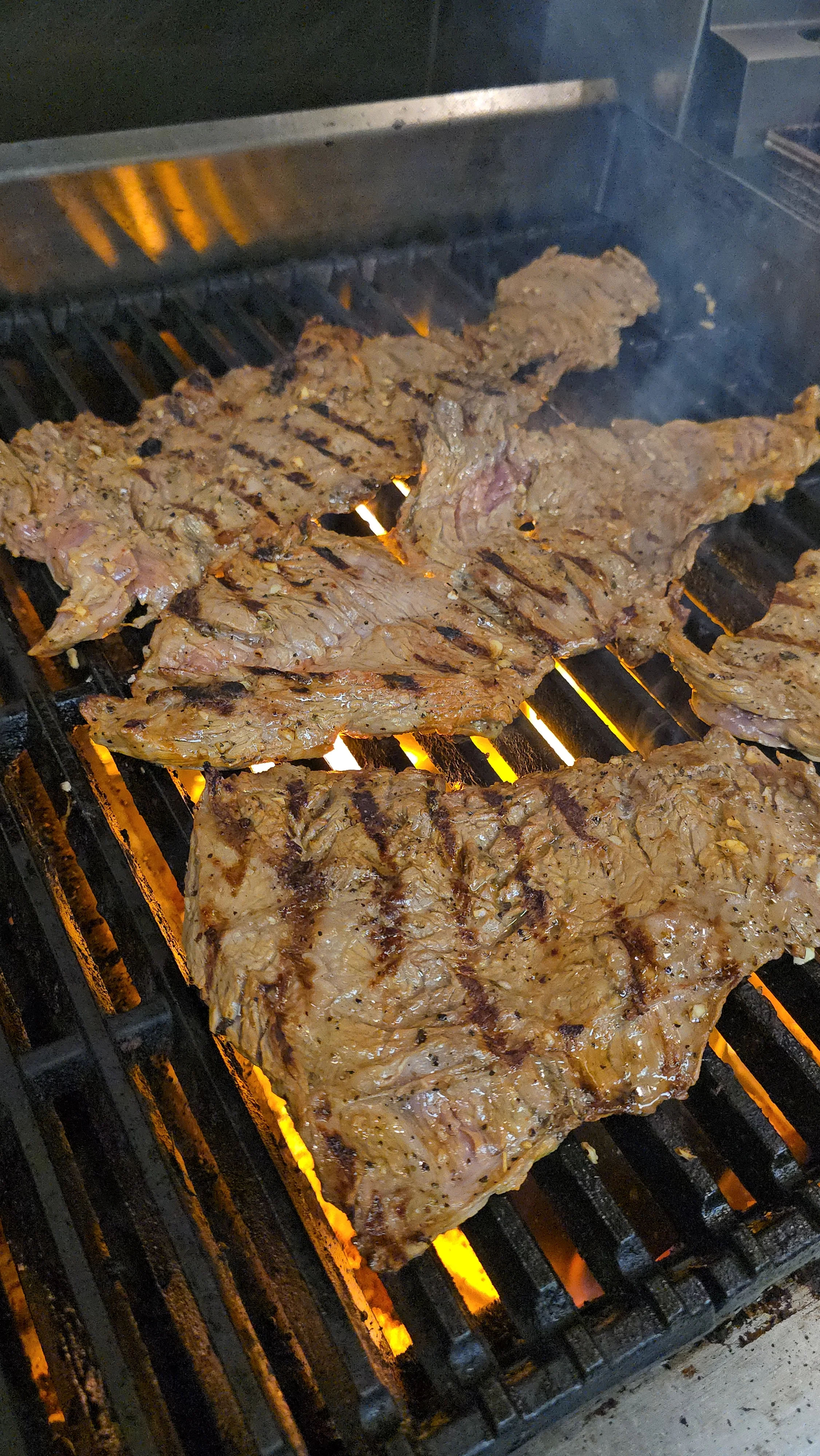 Grilled carne asada sizzling on the barbecue