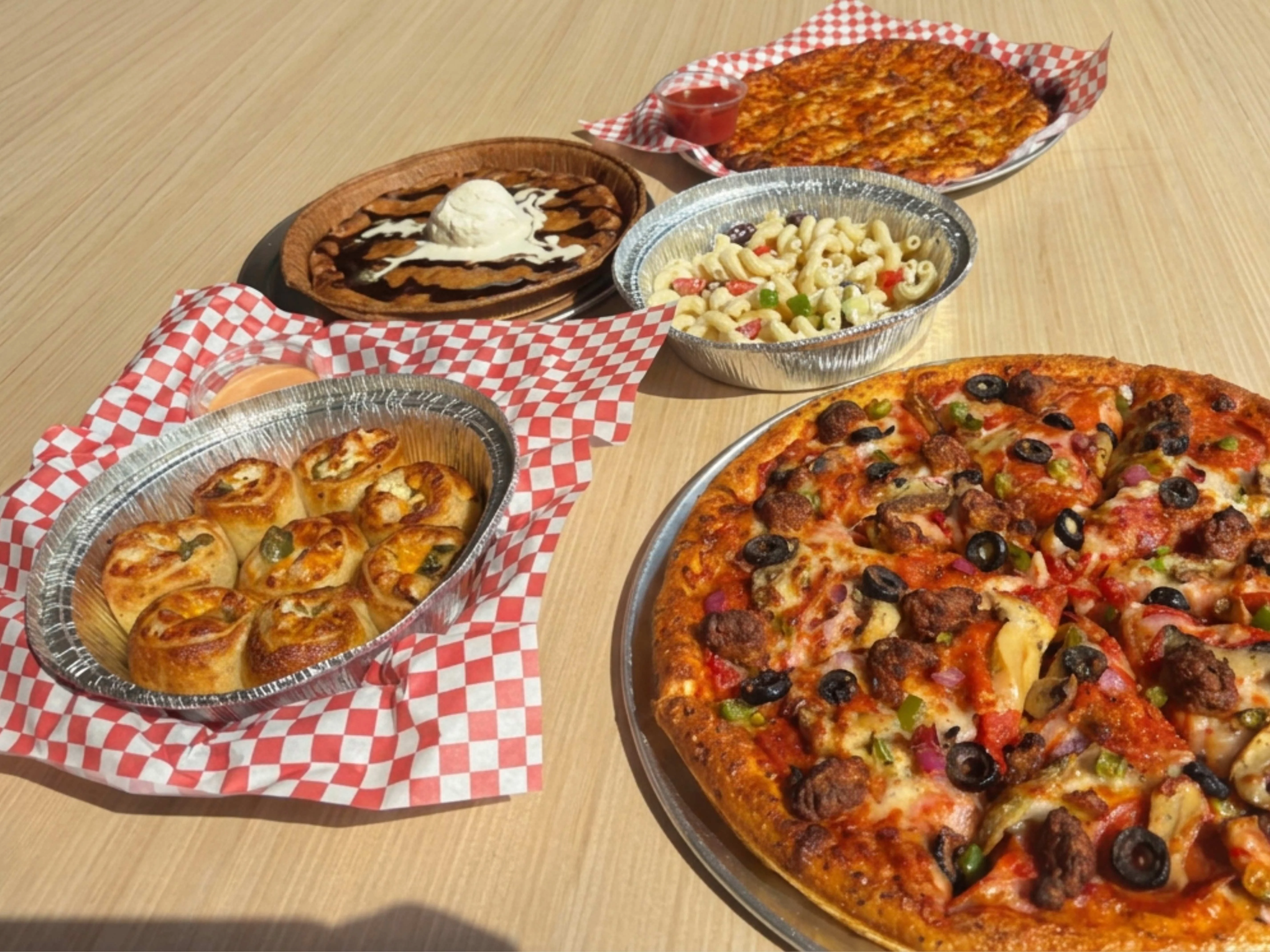 Delicious pepperoni pizza with sides of cheesy rolls and dessert