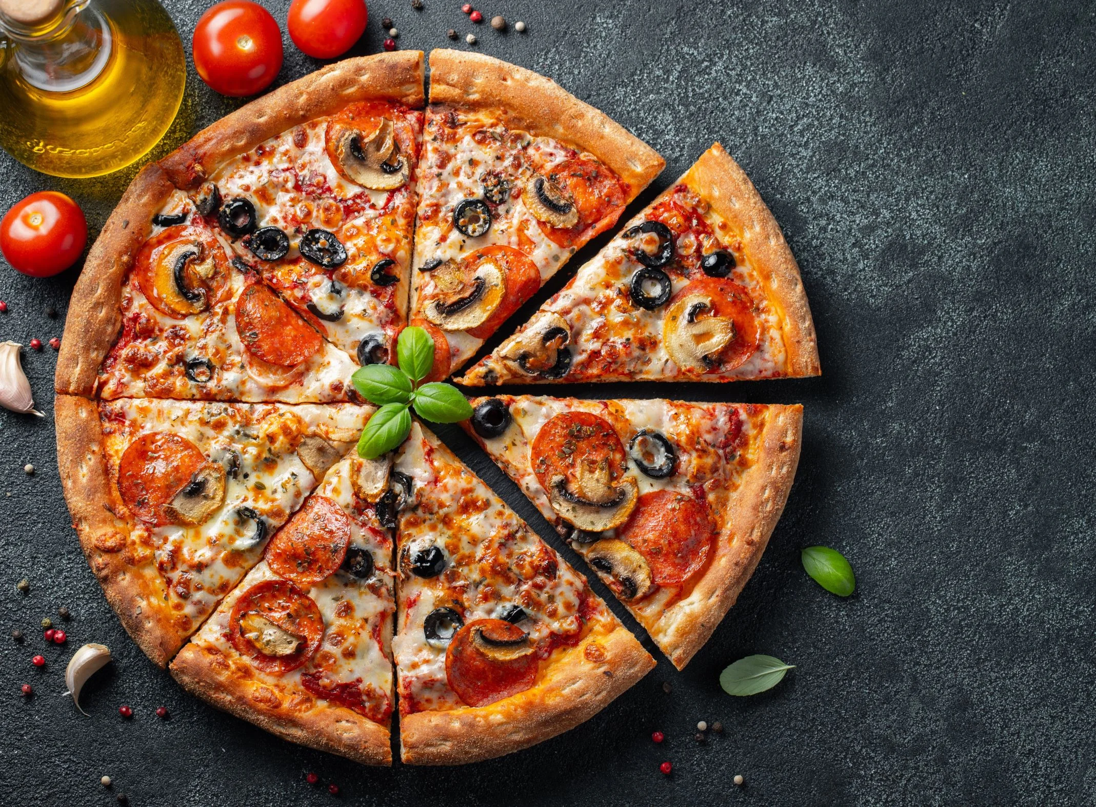 Pepperoni pizza with olives and mushrooms on a dark background