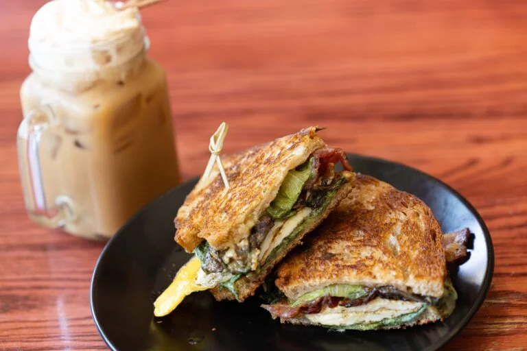 Grilled cheese sandwich with bacon and greens, served with iced coffee