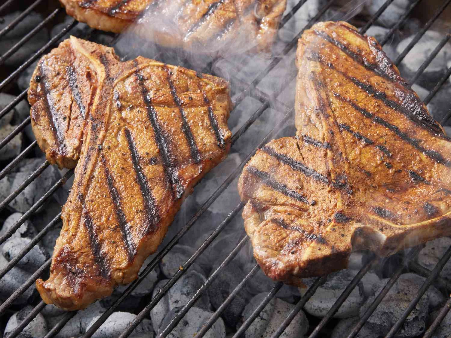 Grilled T-bone steaks with grill marks on a barbecue grill.