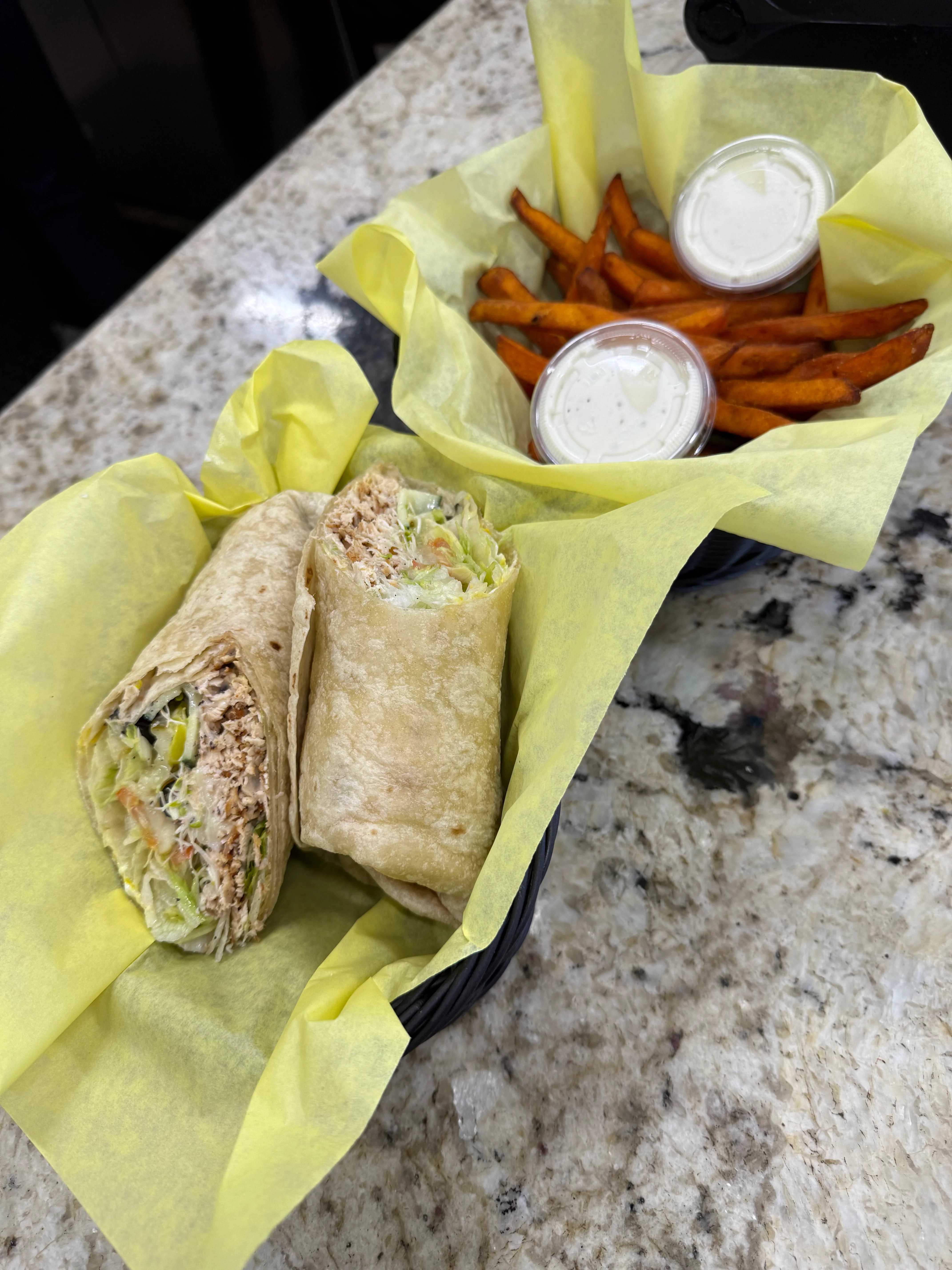 A sandwich with bacon, shredded chicken, and fresh toppings like lettuce and avocados, ready to be served.