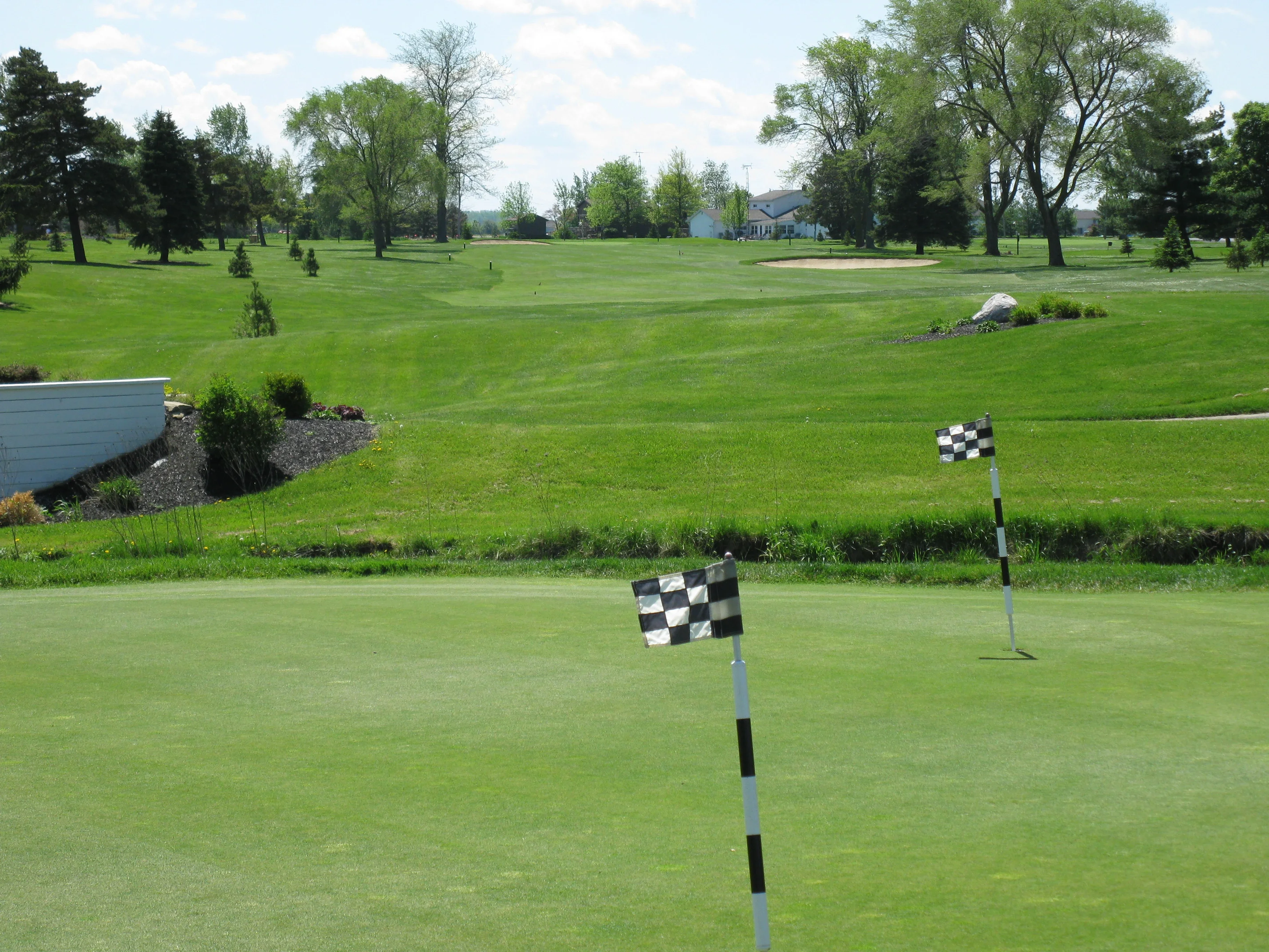 Lush green golf course with flags on putting greens