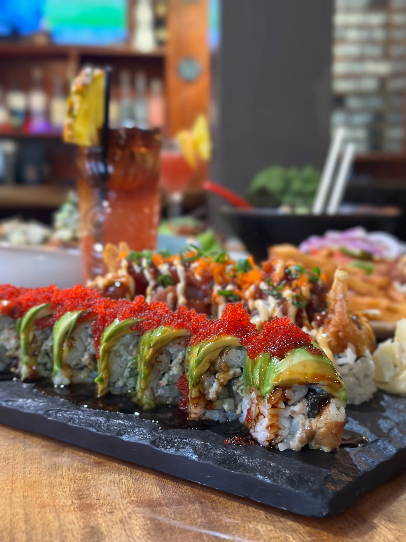 Colorful sushi rolls with avocado and spicy toppings on a slate platter