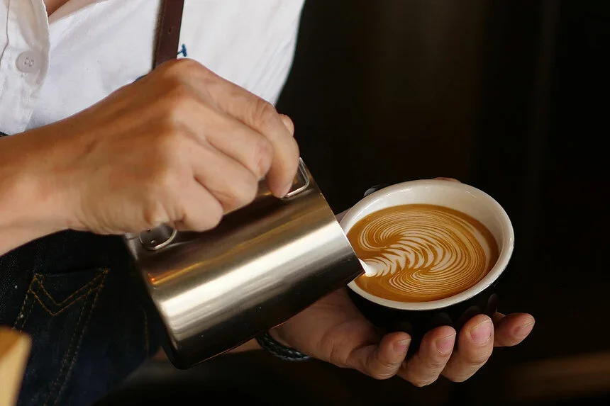 Barista pouring latte art into a coffee cup
