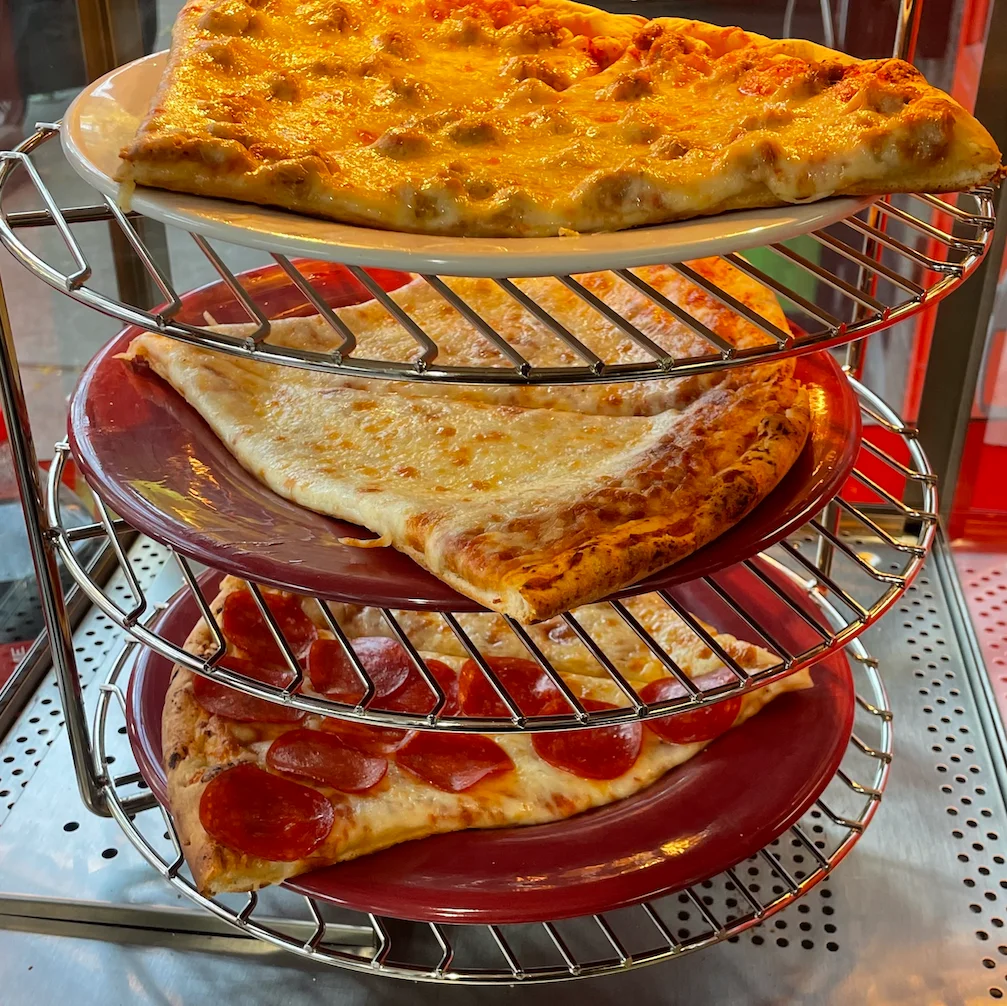 Three slices of classic New York-style pizza on a display rack