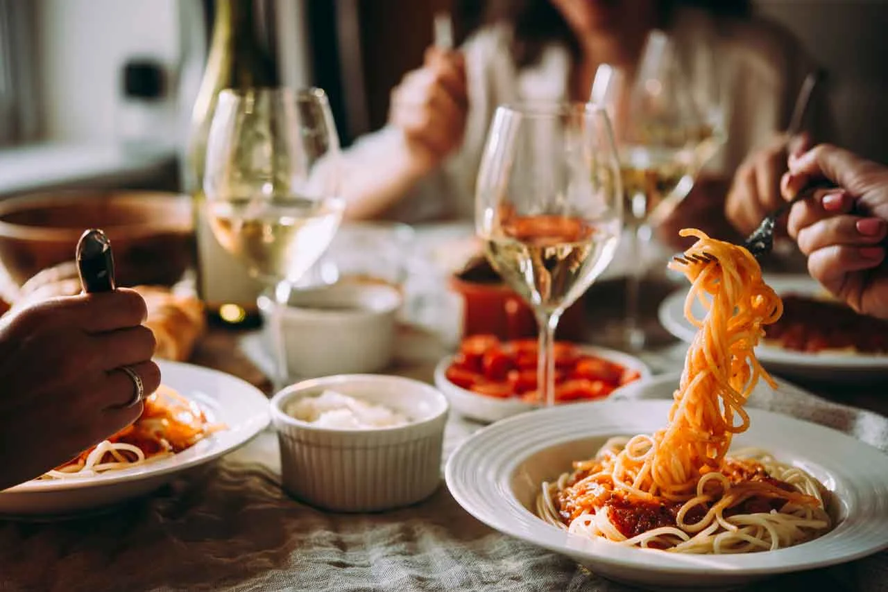 Plate of spaghetti with marinara sauce and wine glasses on a dining table