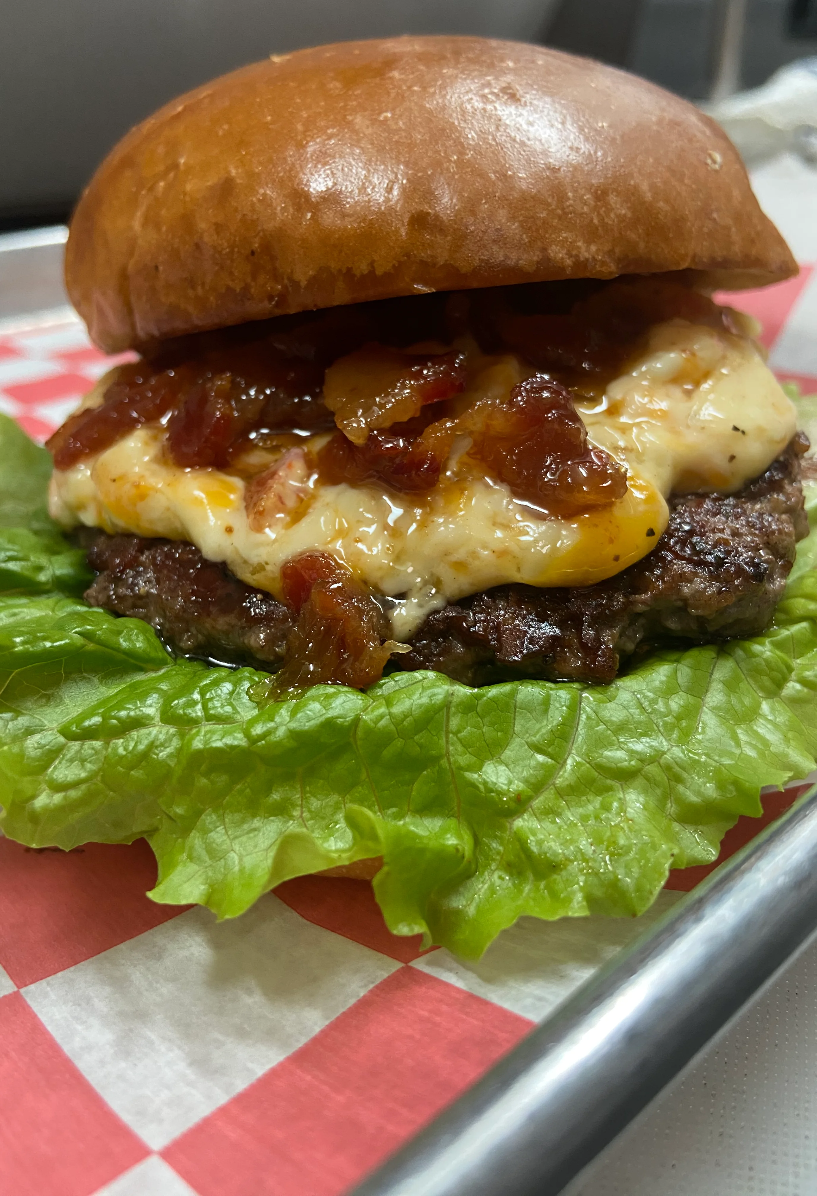 Close-up of a gourmet burger with lettuce, cheese, and sauce on a bun.
