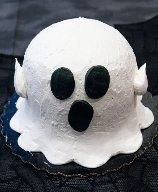 Halloween ghost cake with white frosting and black facial features