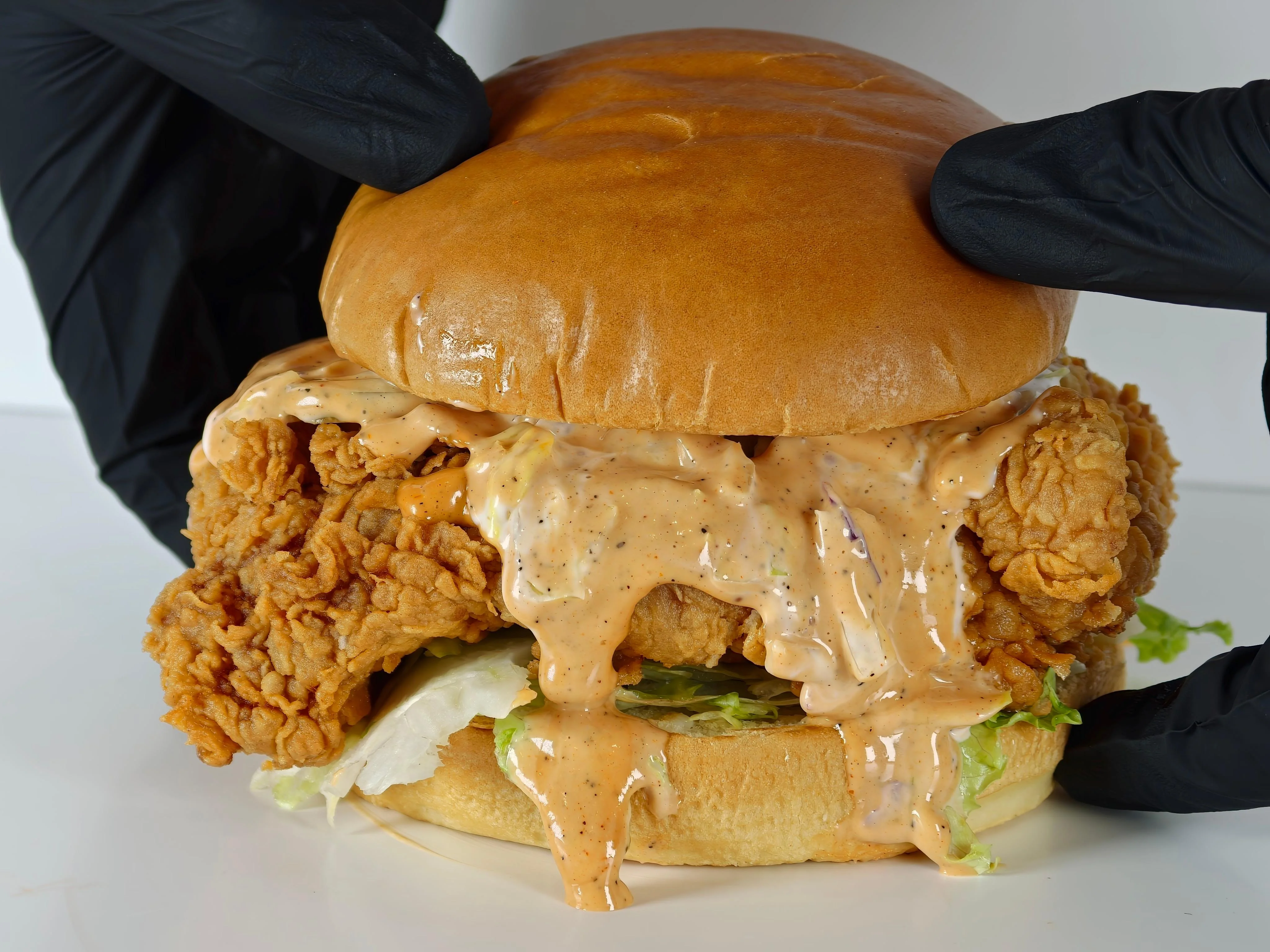 A delicious fried chicken sandwich overflowing with crispy chicken and a creamy sauce, served in a soft bun with lettuce.