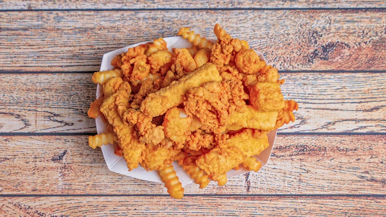 A generous portion of crispy fried chicken mixed with crinkle fries, all served in a white tray.