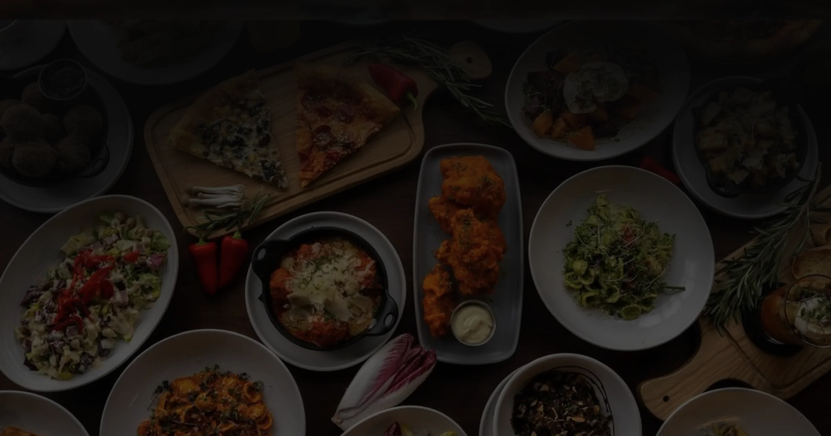 Assorted global dishes including pizza, pasta, and salads on a wooden table