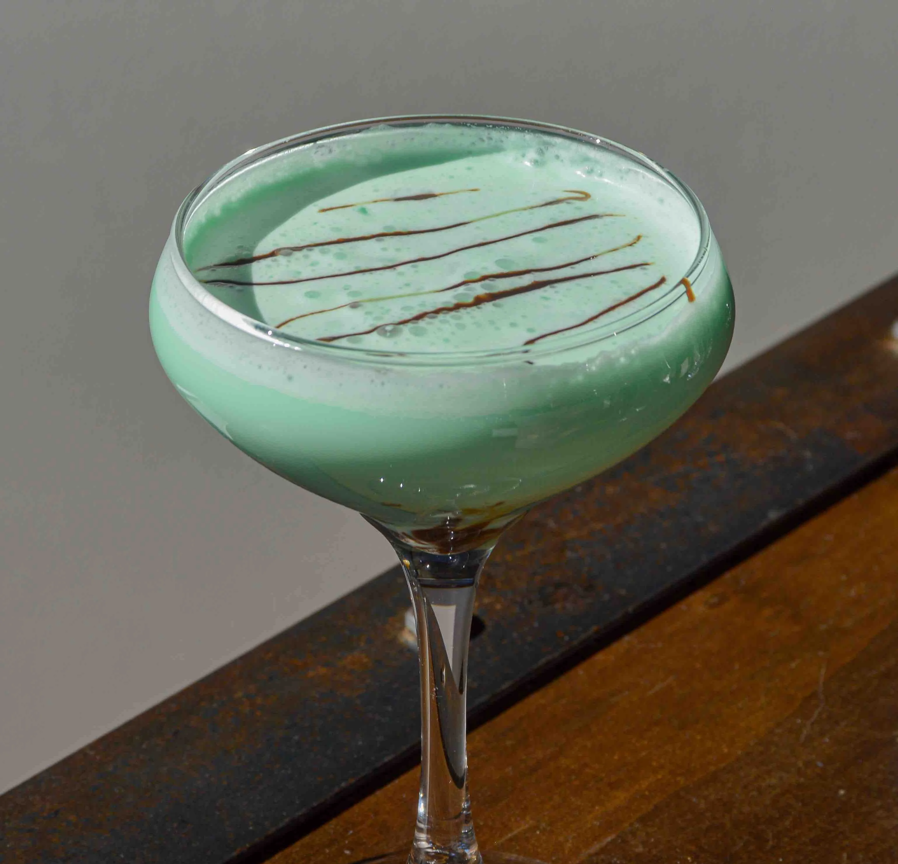 Shamrock-Tini with a drizzle of chocolate syrup across the top of the mint-colored cocktail
